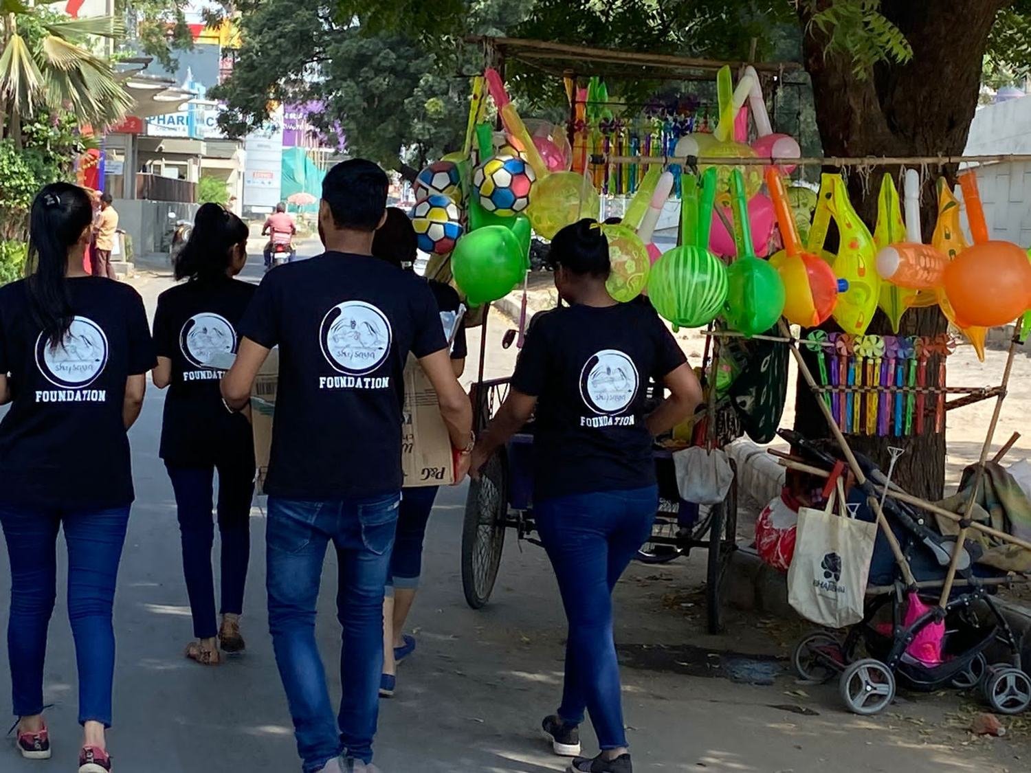 Volunteers walking through a settlement with toys and balloons