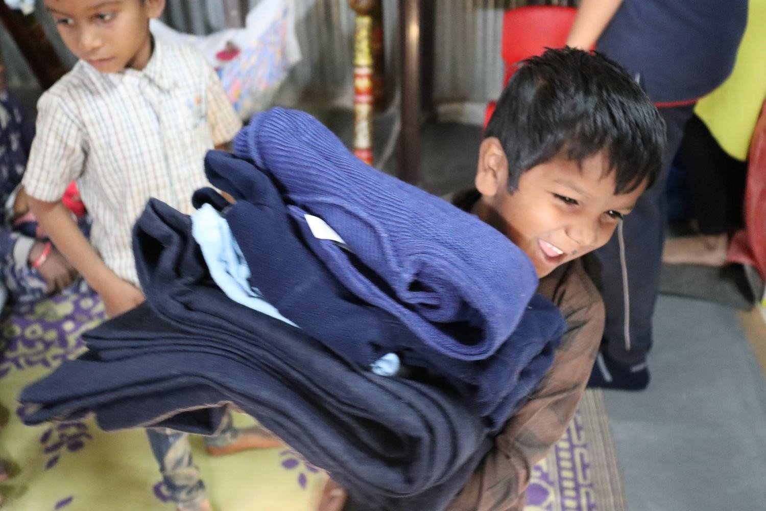 A boy holding a stack of new blankets